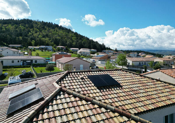 Lotissement avec coline boisée et un toit de maison équipé d'un chauffe eau solaire et de panneaux solaires par ALpha Solaire, entreprise installation panneau solaire ardèche.