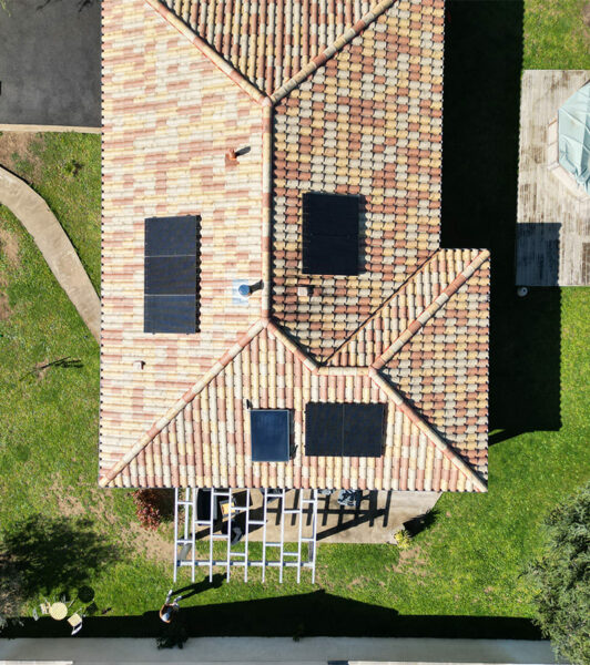 vue aérienne d'un toit de maison aux tuiles colorées avecc 4 panneaux solaires, par Alpha Solaire, entreprise installation panneau solaire ardèche.