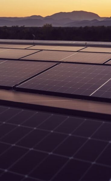 panneau solaire bâtiment industriel au soleil couchant montagne en arrière plan.