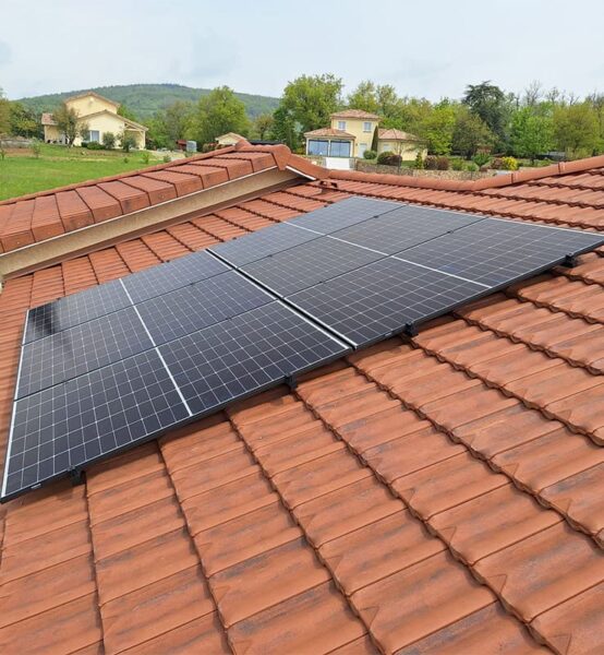 Un projet Alpha Solaire, entreprise installation panneau solaire ardèche, des panneaux solaires sur cette toiture rouge, deux maisons dans le fond.