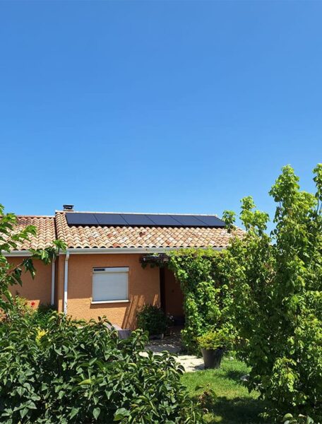 Panneaux solaires particulier pour une maison façade orange et volet blanc fermé.
