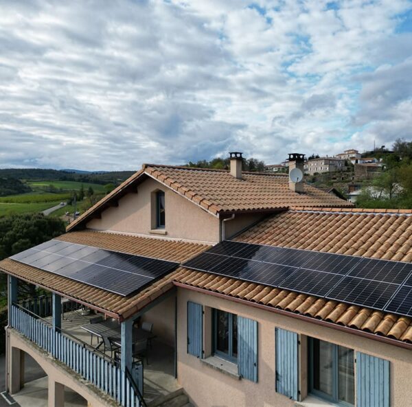 Maison à double étage avec terrasse et volets bleus, panneaux solaires par Alpha Solaire, entreprise installation panneau solaire ardèche.